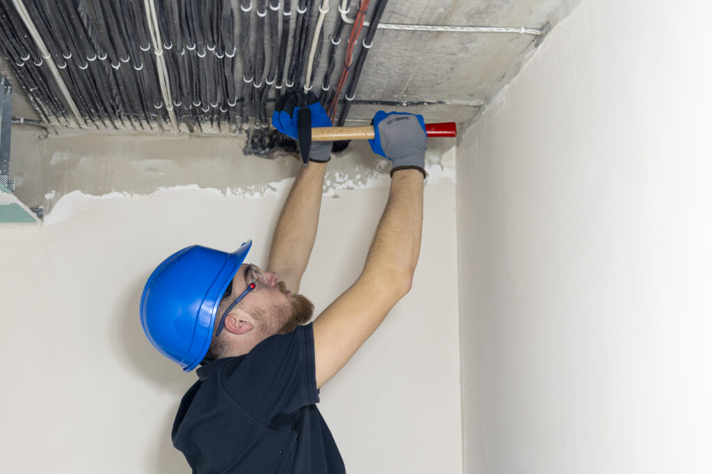electrician installing laying electrical cables on the ceiling inside the house.